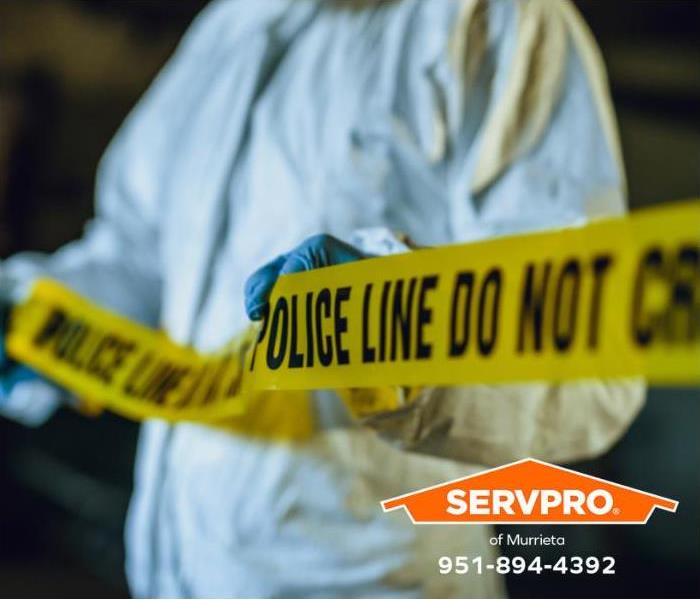 A crime scene technician is placing yellow crime scene tape to prevent onlookers from entering an active crime scene.