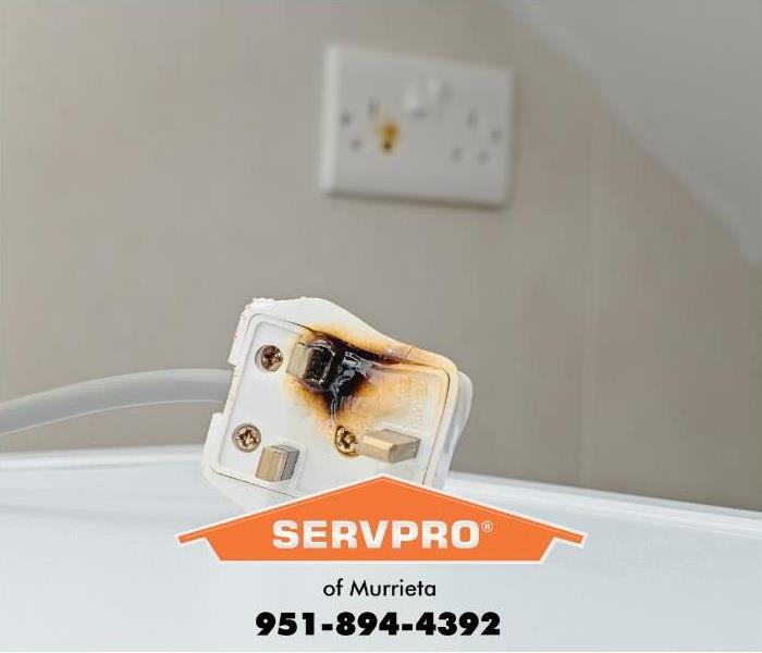A burnt refrigerator plug and outlet are shown inside a kitchen.