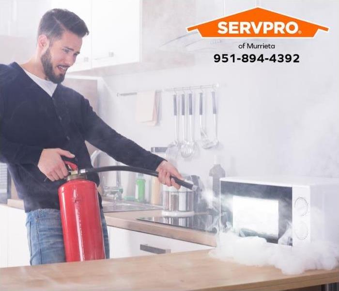 A person uses a fire extinguisher to put out a fire in a microwave oven. 